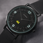 A Petronas wristwatch with a black round case, black mesh strap, and a black dial featuring white Arabic numerals and a bright yellow '44' at the 6 o'clock position.
