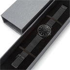 Watch with black mesh strap in a gray box on a white background