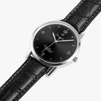 A wristwatch with a black dial, silver-tone case, and black leather strap, shown diagonally on a light gray background.