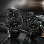 Two black leather-strand wristwatches with black dials and silver-tone hands, one large and one small, both branded Joventra, displayed on a dark reflective surface.