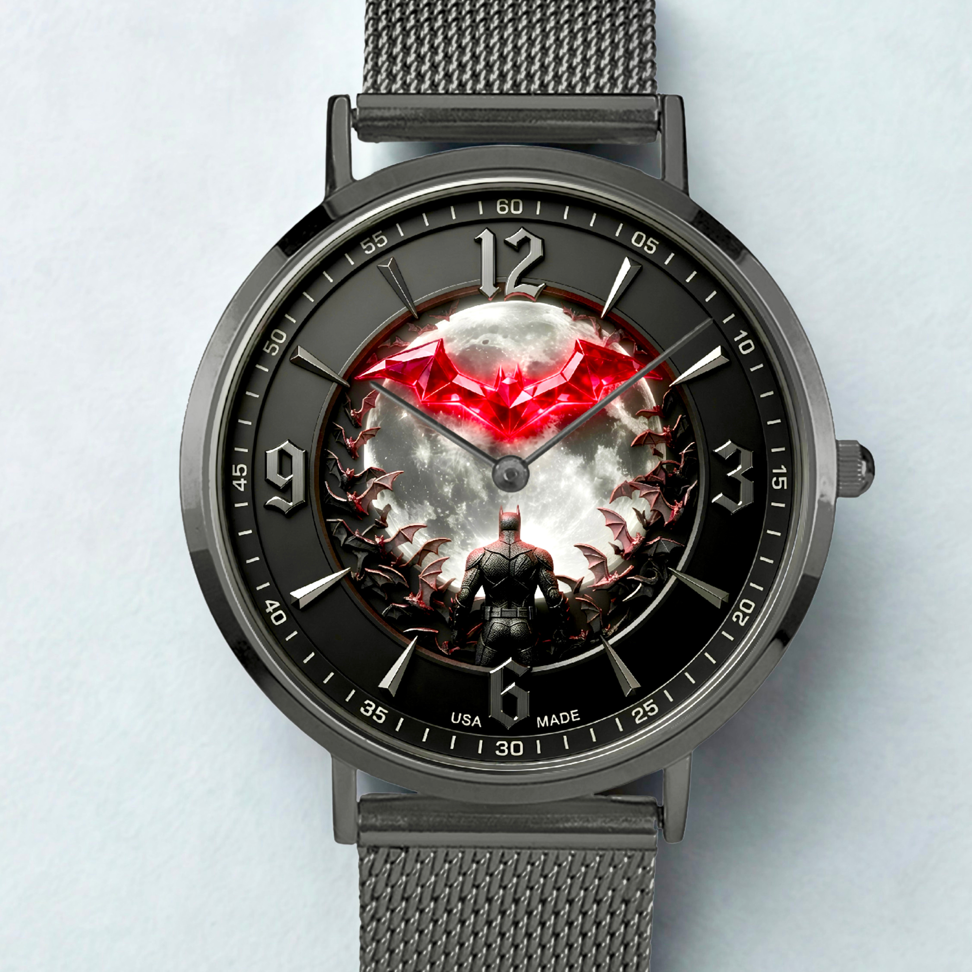 A dark gray metal mesh-strand bracelet watch with a round case and a highly detailed graphic dial. The dial features a black background with a glowing red bat emblem at the 12 o'clock position, a central white and gray cloud-like pattern, and a dark figure at the bottom.