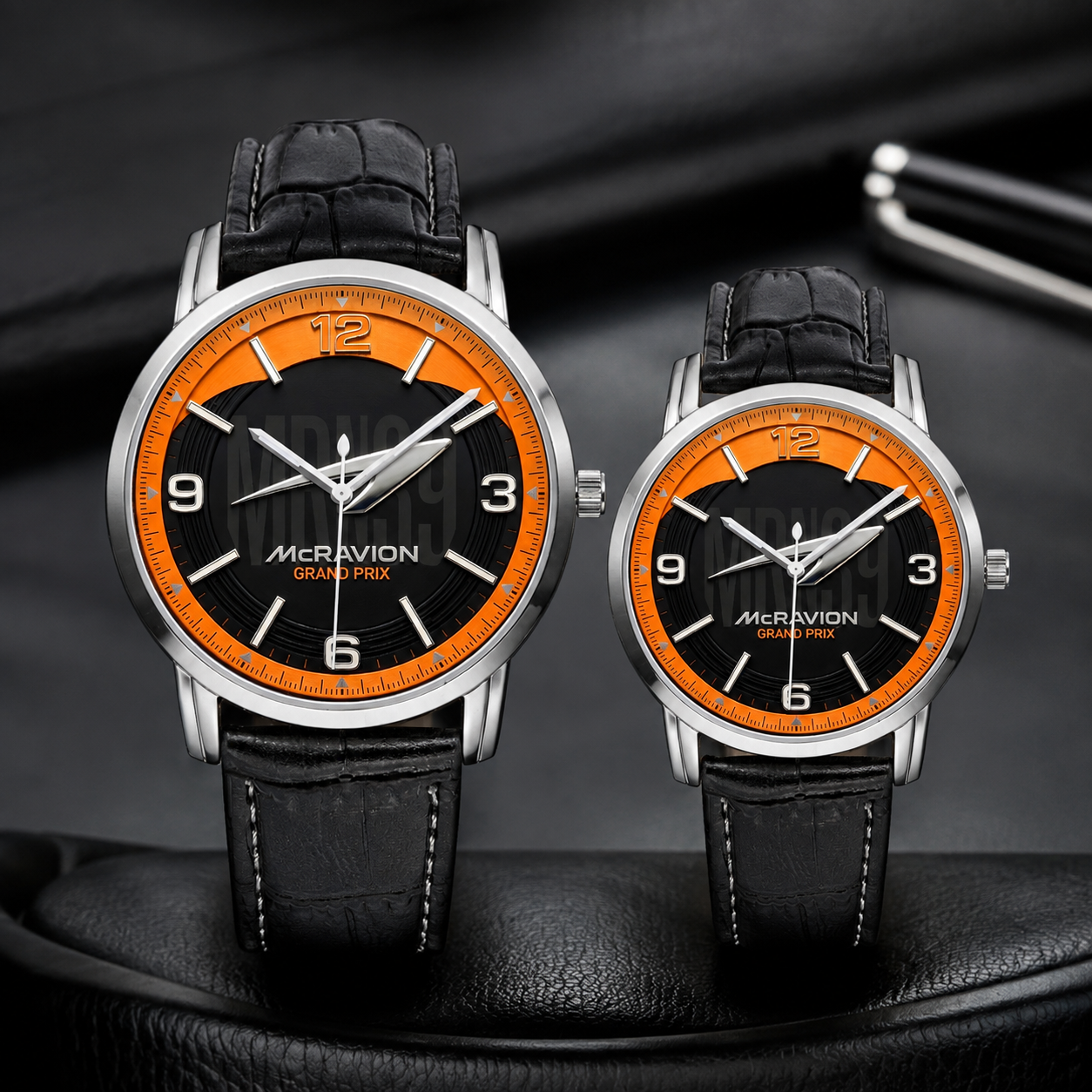 Two Mcravion Grand Prix analog wristwatches with black leather straps and black-and-orange dials, displayed on a dark textured surface.