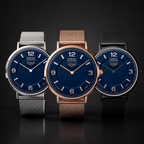 Three ALPHA Crystal Sports watches with deep blue dials and mesh straps, shown in silver, rose gold, and black metal finishes against a dark background.