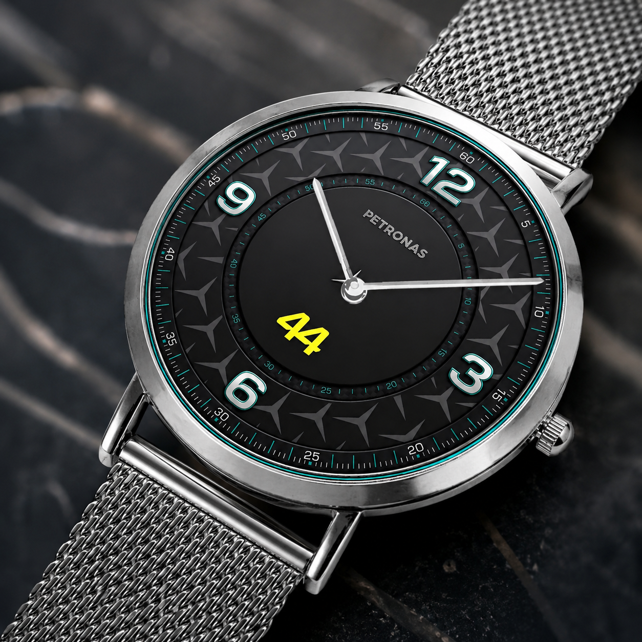 A Petronas wristwatch with a silver mesh strap, round silver case, and a black dial featuring white Arabic numerals and a bright yellow '44' in the center, shown on a dark textured background.