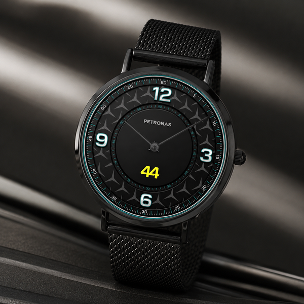 A Petronas wristwatch with a black mesh strap, black round case, and a black dial featuring white Arabic numerals and a bright yellow '44' at the bottom, set against a dark metallic background.