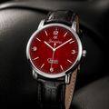 A close-up of a Joventra Classic Timelapse wristwatch with a deep red dial, silver-tone case, and black leather strap, resting on a dark textured surface.