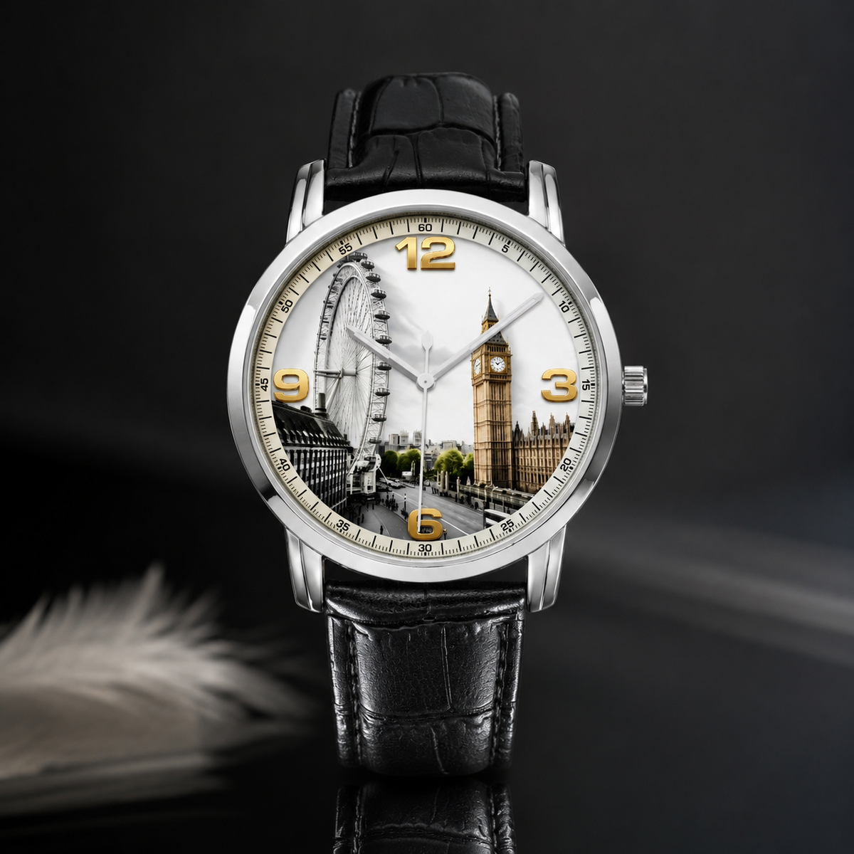 A wristwatch with a silver-toned case, black leather strap, and a London-themed dial featuring Big Ben and the London Eye. The watch is centered against a dark studio background with a soft feather prop in the lower left.