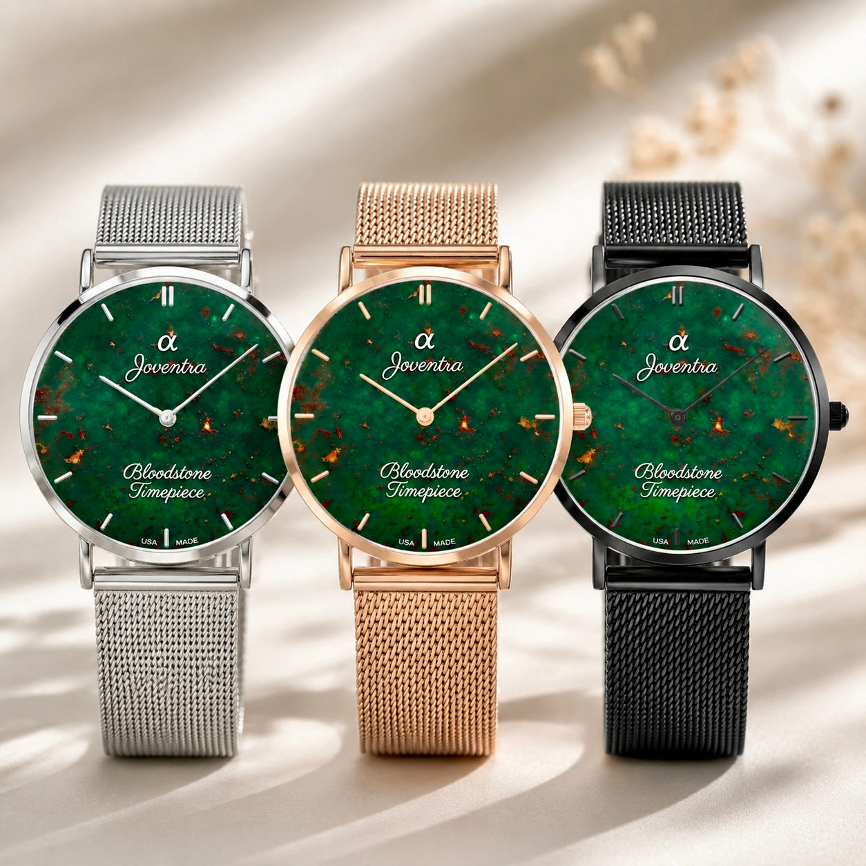 Three Joventra Bloodstone Sympaace wristwatches with green marbled dials and mesh straps in silver, gold, and black, arranged side by side on a light beige background with soft shadows.