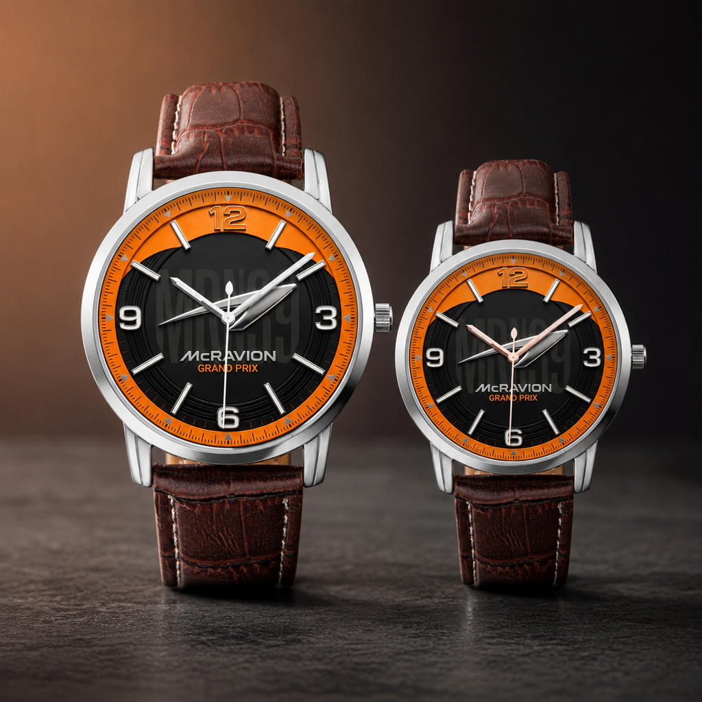 Two McRavion wristwatches with brown leather straps and silver cases, featuring black and orange dials, displayed side by side on a dark surface.