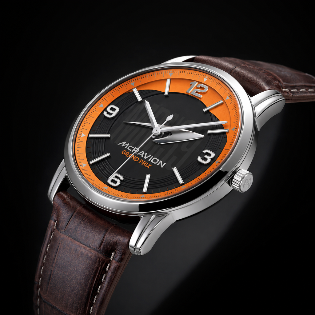 A close-up studio shot of a wristwatch with a brown leather strap, a silver-toned case, and a black dial featuring a bright orange inner ring. The Joventra McRavion brand name is printed on the dial.