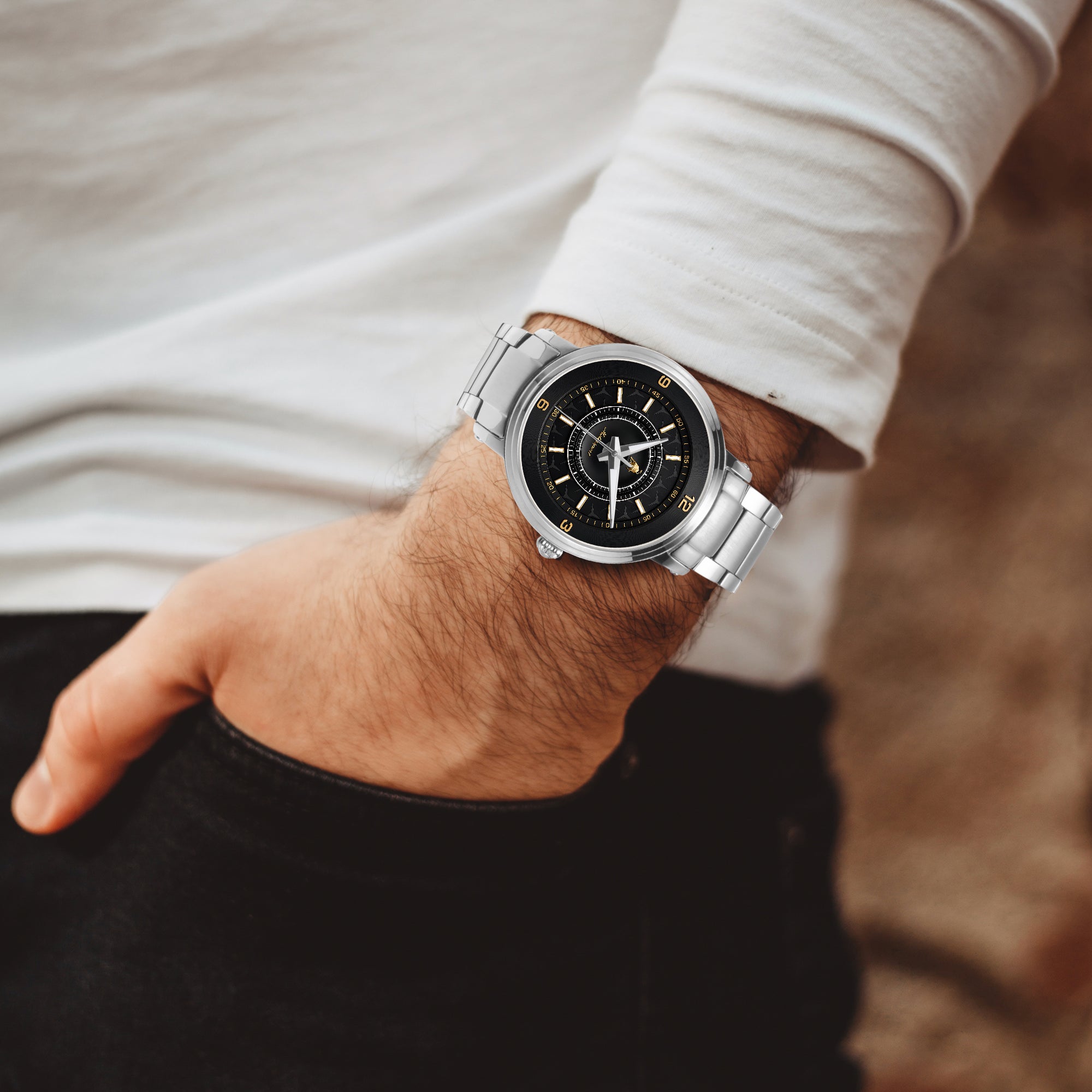 Silver watch with black face on a wrist, blurred background