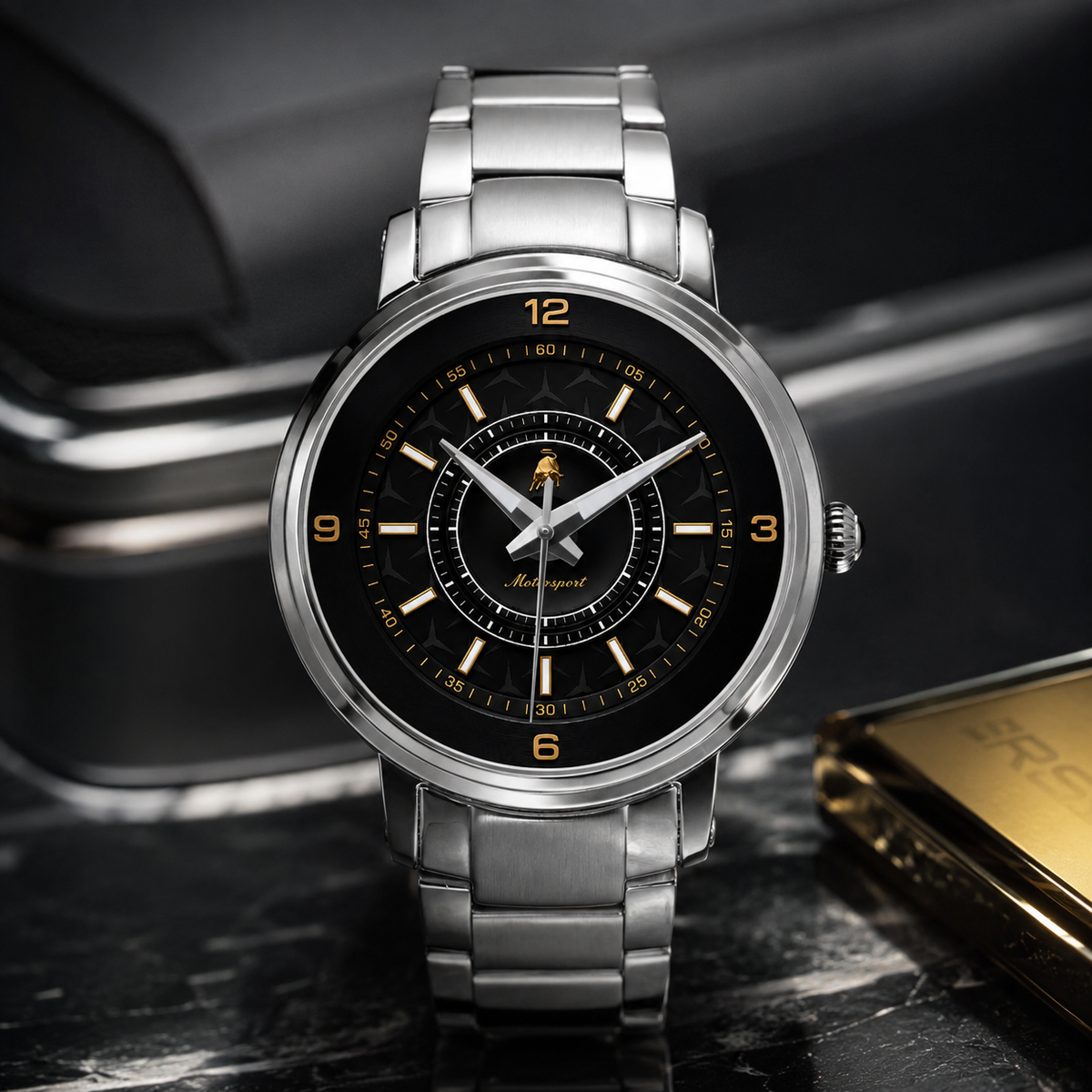 A silver stainless steel wristwatch with a black dial, gold-tone numerals and hands, and a matching metal link bracelet, displayed on a dark marble surface with a blurred car interior in the background.