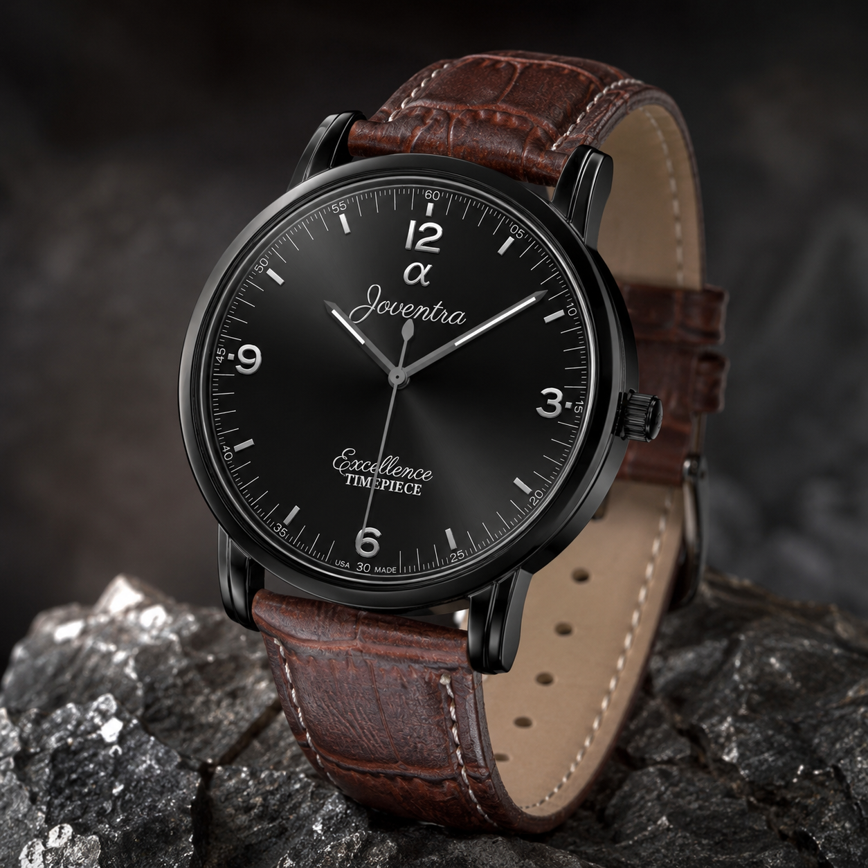 A luxury wristwatch with a black dial, black bezel, and a brown leather strap, resting on dark rocks. The dial features the brand name 'Joventra' and the model 'Excellence Timepiece'.