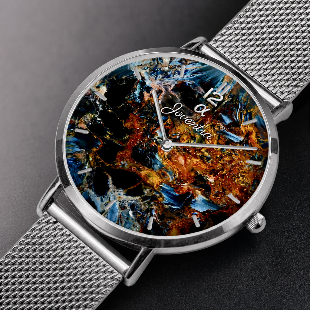 A close-up of a wristwatch with a silver mesh metal band and a round silver case. The dial features an abstract, textured painting with black, blue, orange, and gold tones, with the brand name 'Jewerka' written in white script.