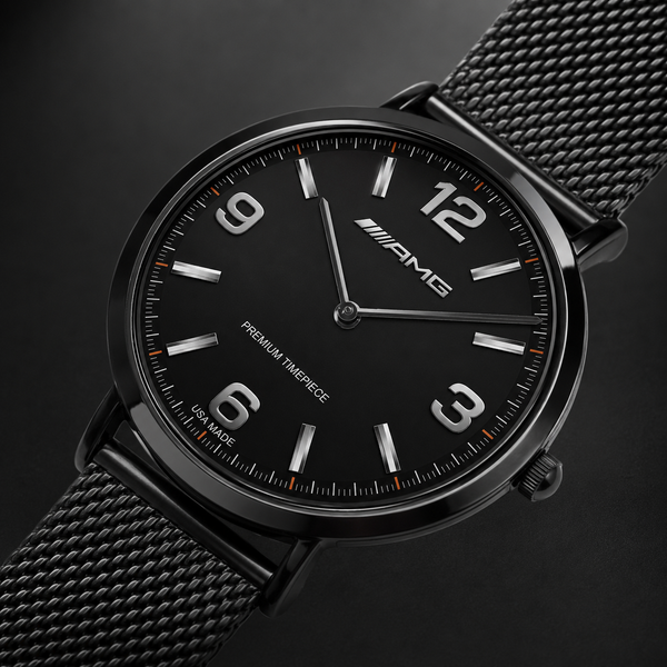 A close-up studio shot of a black Mercedes-AMG wristwatch with a black mesh metal band, featuring silver-tone numerals and hands with subtle orange accents on the dial.