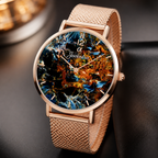 A close-up of a women's Joventra Celestial analog watch with a rose gold mesh strap and a colorful, abstract mineral-like dial featuring blue, gold, and black tones.