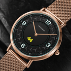 A close-up of a Petronas wristwatch with a rose gold mesh strap, a black dial with white Arabic numerals, and a yellow '44' display on a dark textured background.