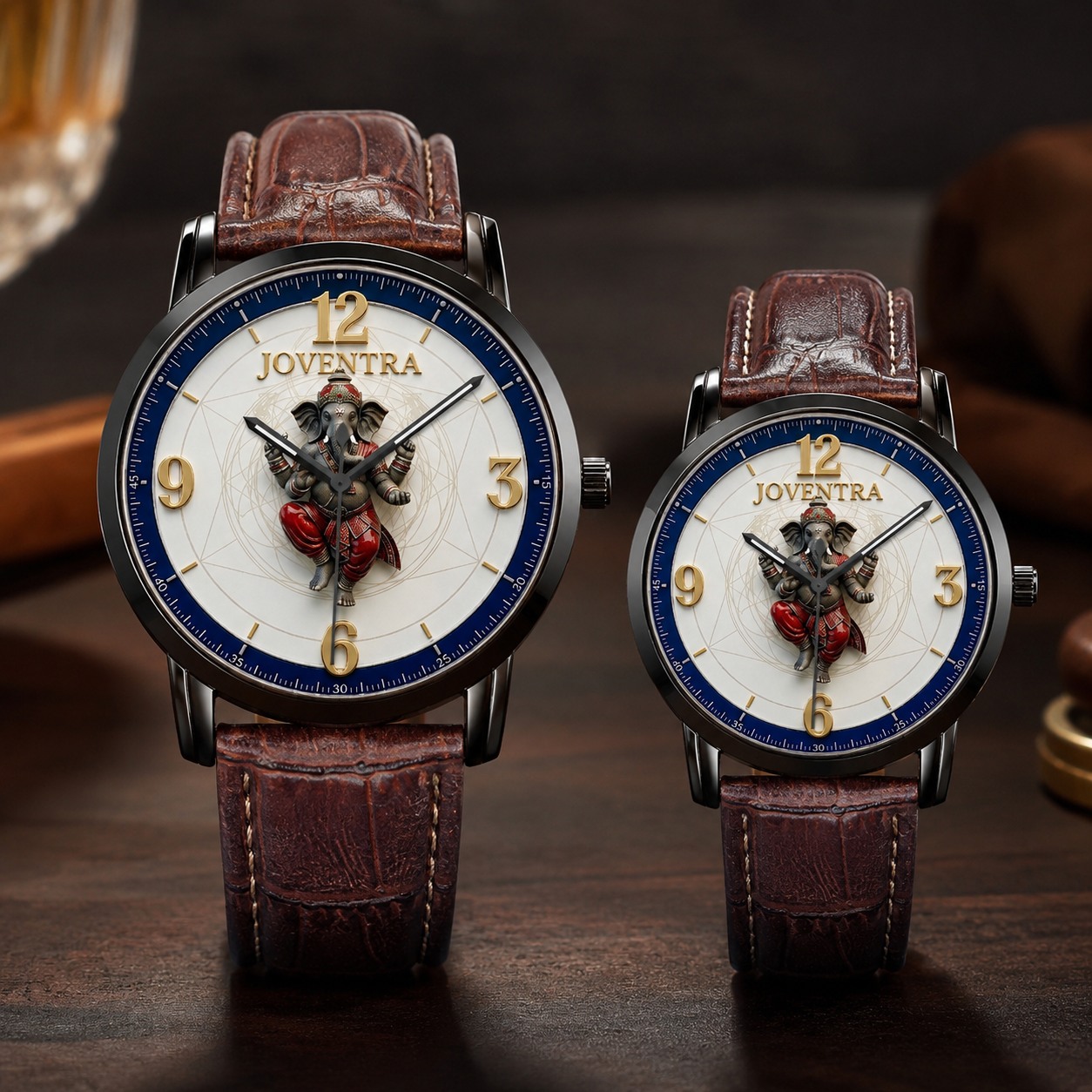 Two matching wristwatches with brown leather straps and round white dials, displayed on a dark wooden surface. The dials feature a blue inner ring, gold Arabic numerals, and a central 3D figure of Ganesha.