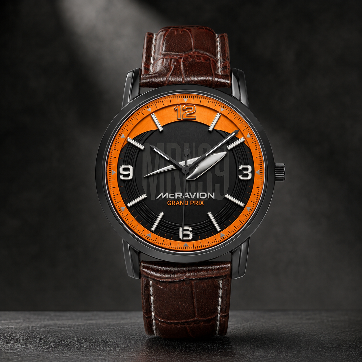 A luxury wristwatch by McRavion Grand Prix, featuring a dark gray case, a black dial with a vibrant orange inner ring and white numerals, and a brown crocodile-embossed leather strap.