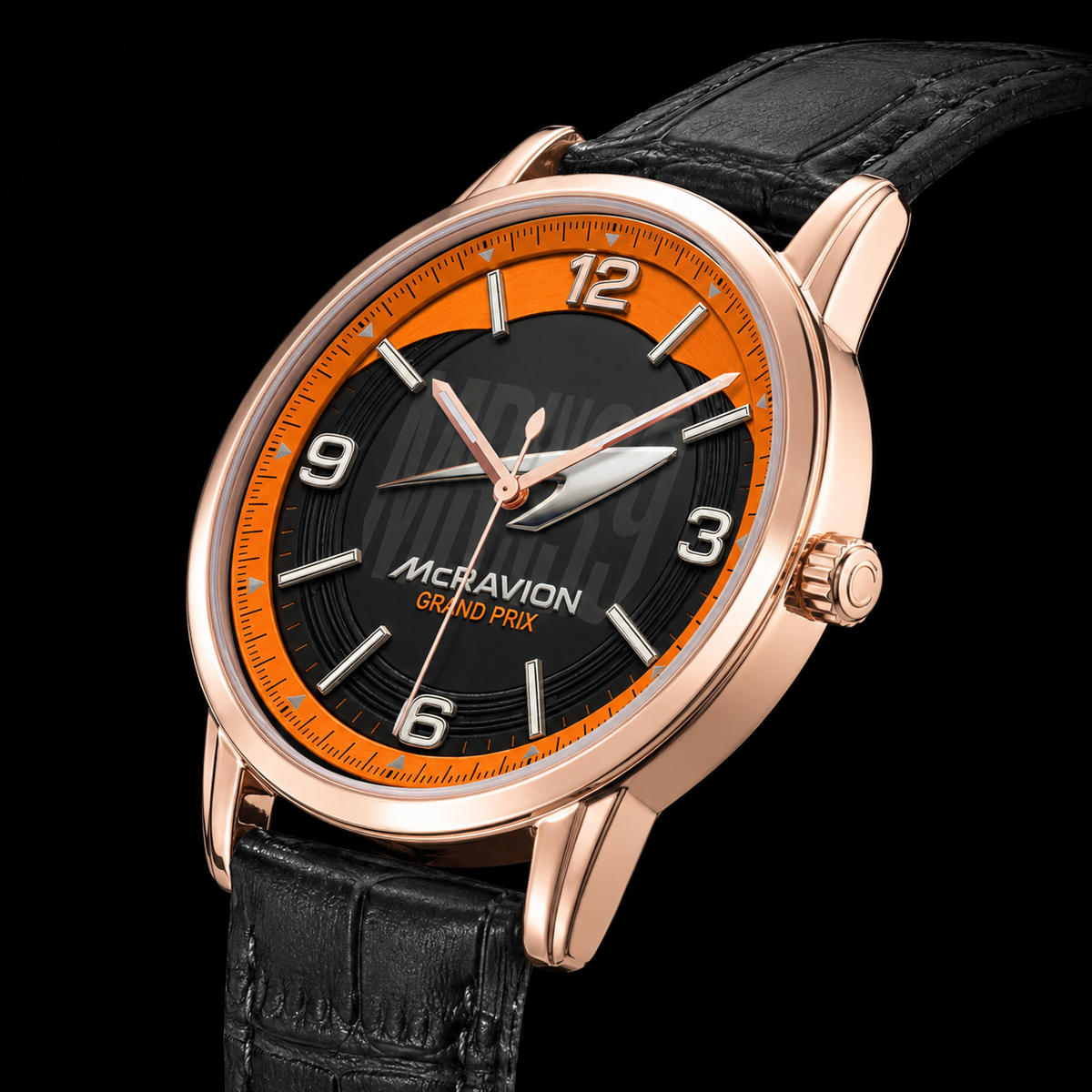 A close-up studio shot of a wristwatch with a rose gold case, black dial, bright orange inner ring, and black leather strap on a black background.