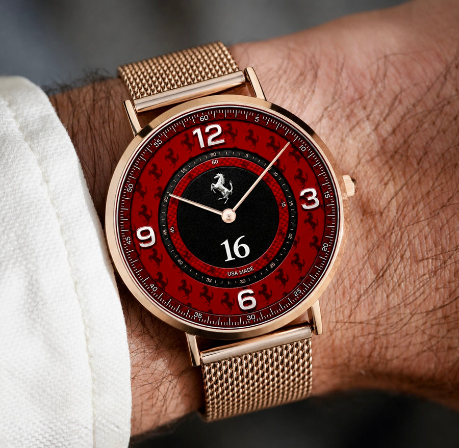 A close-up of a wrist wearing a Joventra Italian Motorsport watch with a rose gold mesh strap, a red dial with black inner ring, white numerals, and racing-inspired dial graphics.