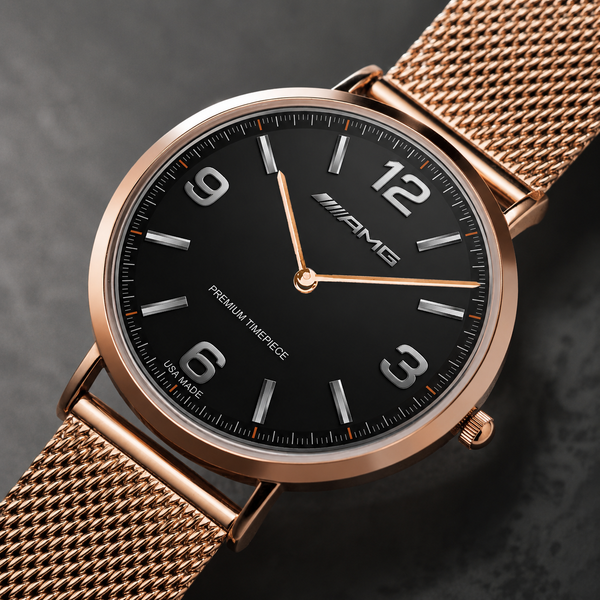 A close-up of a Mercedes-Benz AMG wristwatch featuring a black dial, rose gold case, and matching rose gold mesh strap, set against a dark textured background.